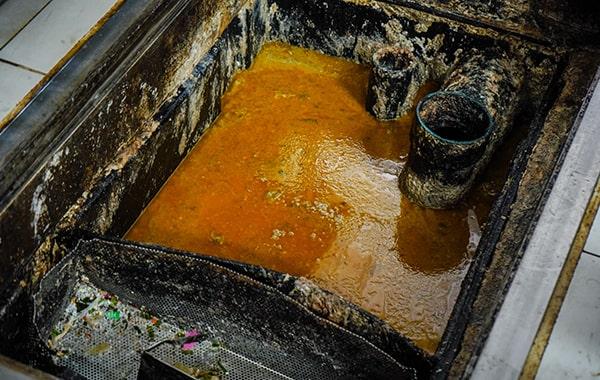 during grease trap cleaning, the trap is emptied, scraped, and washed to remove built-up grease and solids